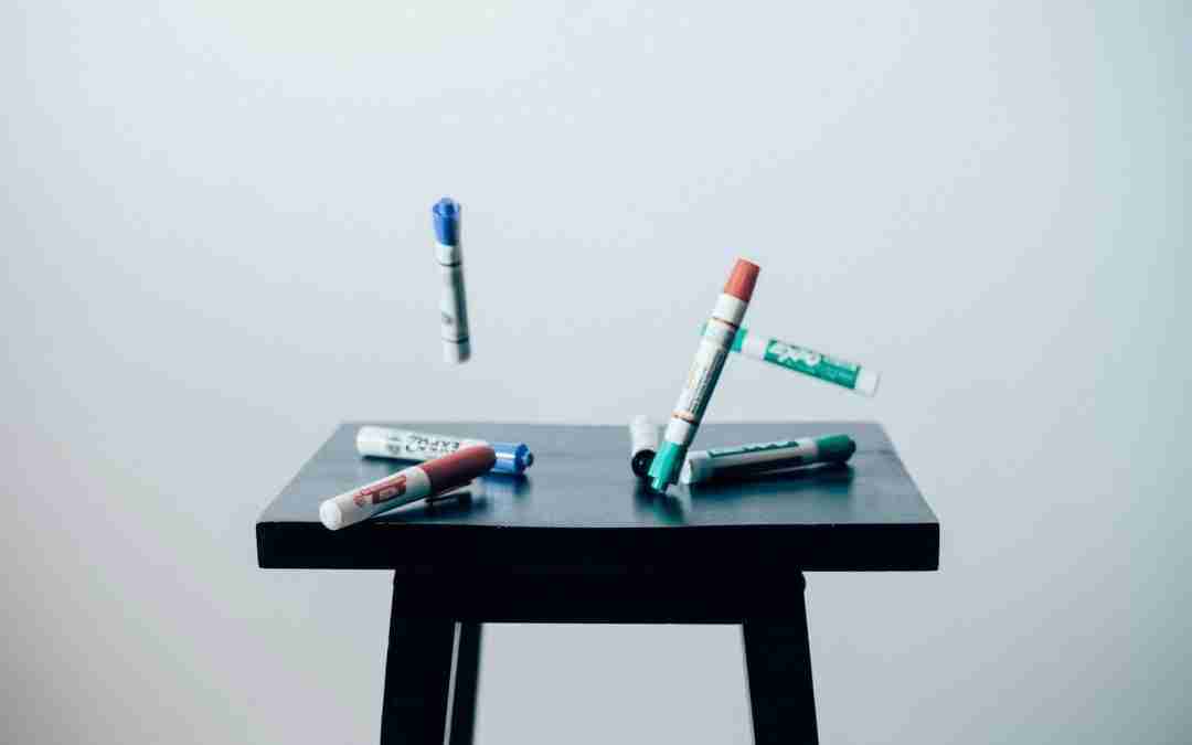 timelaps photo of assorted-color pen on brown wooden saddle stool chair